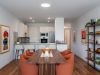 Optima Verdana luxury apartment with Modern dining area with orange chairs, wooden table, and open kitchen—Optima home interiors elevate stylish kitchen design and décor.