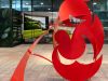Optima Verdana luxury apartment with Bright red abstract metal sculpture with curved and circular shapes, displayed in an indoor public space.
