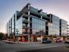 Optima Verdana luxury apartment with Modern glass apartment building with balconies on a city corner at dusk, cars and pedestrians at the intersection.