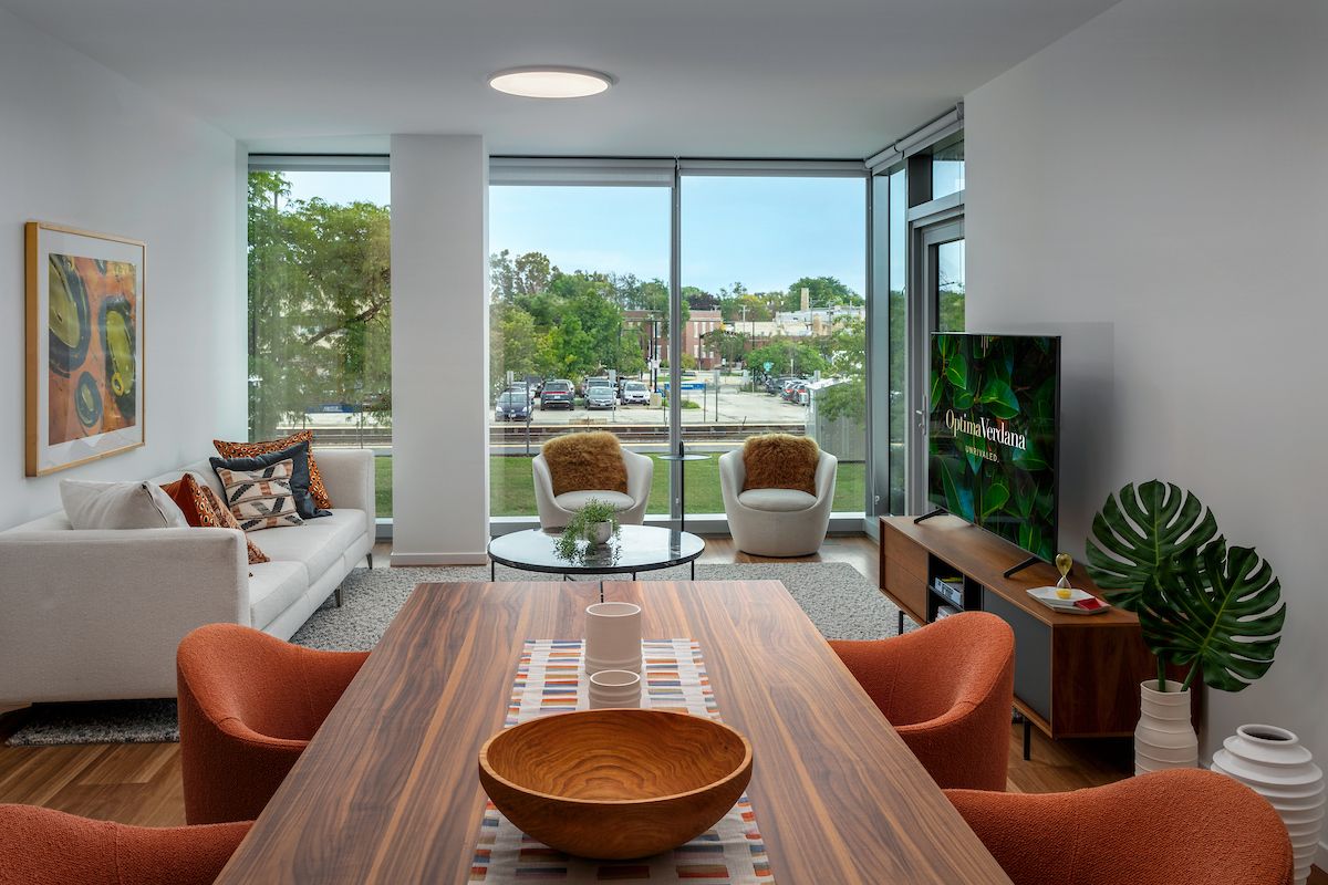 Optima Verdana luxury apartment with Modern living and dining room with large windows, stylish furniture, and a view of a parking lot outside.