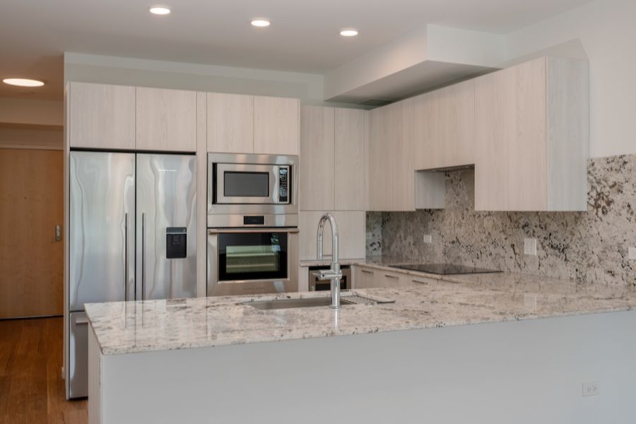 Optima Verdana luxury apartment with Modern kitchen with stainless steel appliances, marble countertops, and light wood cabinets.