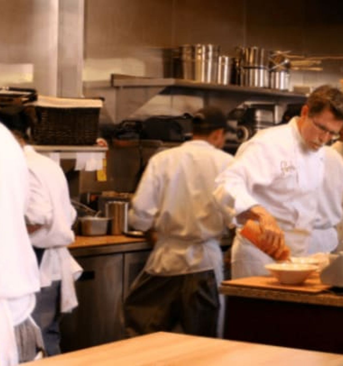 Optima Verdana luxury apartment with Chefs in white uniforms prepare food and work together in a busy kitchen during Chicago Restaurant Week 2024.