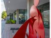 Optima Verdana luxury apartment with Red abstract metal sculpture and modern furniture enhance Optima's Lobbies near a building with large windows and a sidewalk.