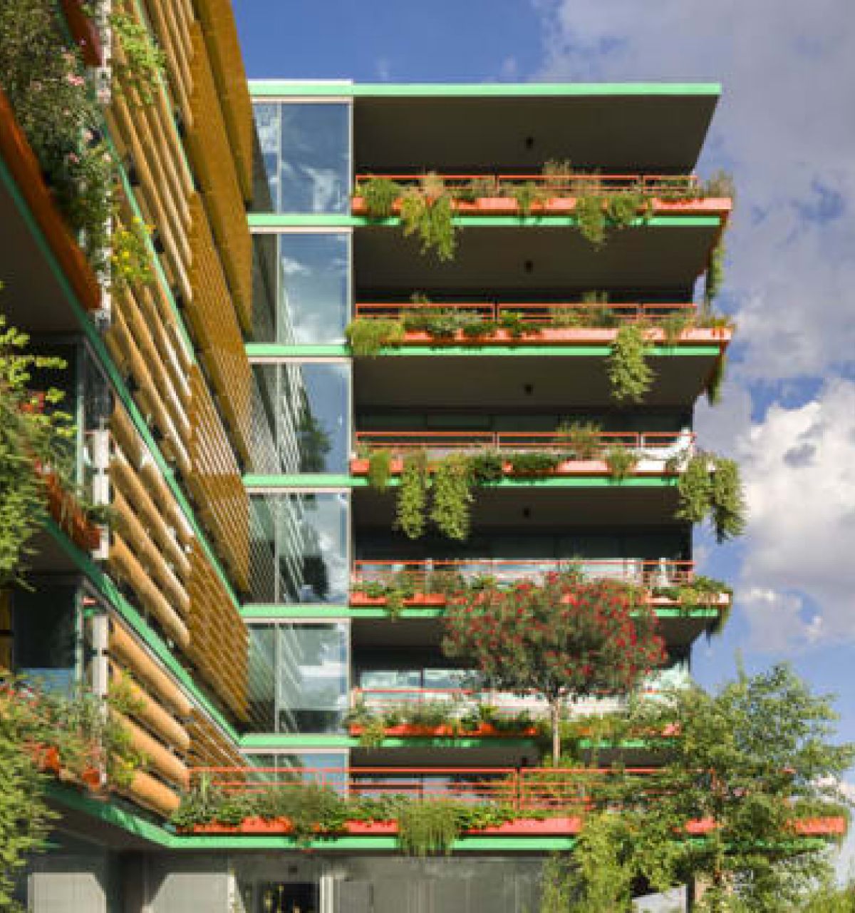 Optima Verdana luxury apartment with Modern building with colorful balconies, lush green walls, and vibrant plants, set against a blue sky and distant mountain.
