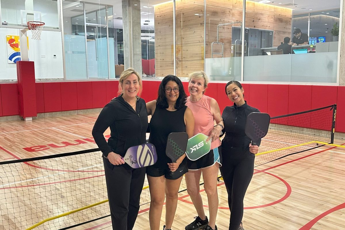 Optima Verdana luxury apartment with Four women smiling and holding pickleball paddles on an indoor court, part of our active pre-move checklist.
