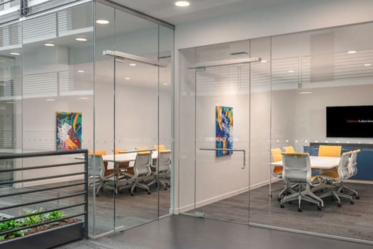 Optima Verdana luxury apartment with Modern glass-walled conference room by Optima Communities with white chairs, a large screen, and colorful abstract art, ideal for hybrid working.
