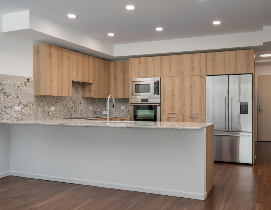 Optima Verdana luxury apartment with Modern kitchen with wood cabinets, marble countertops, stainless steel appliances, and recessed lighting.