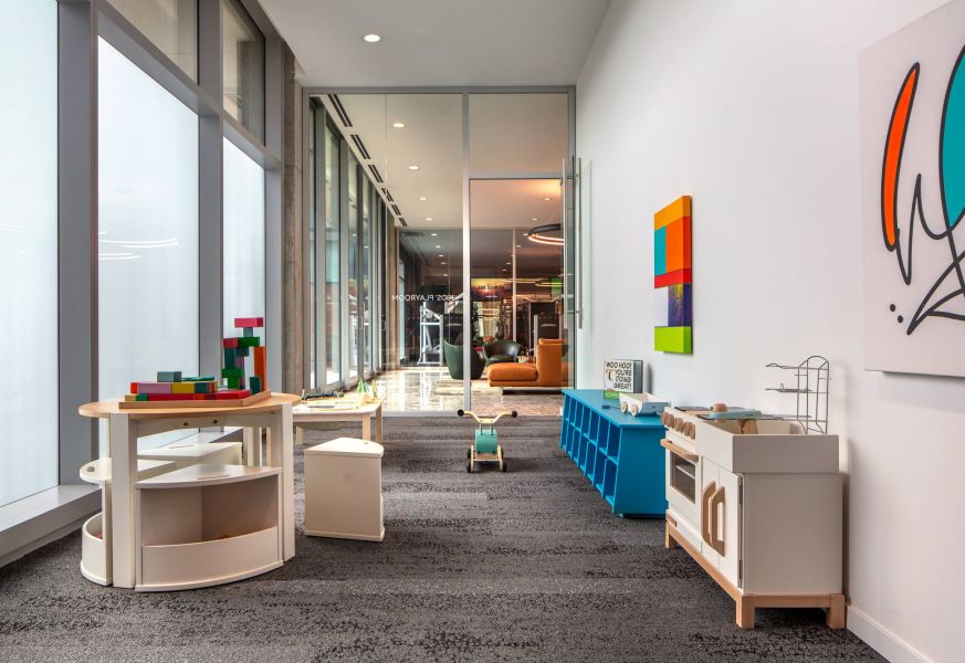 Optima Verdana luxury apartment with Modern playroom with toy kitchen, blocks, and colorful wall art, featuring large windows and bright natural light.