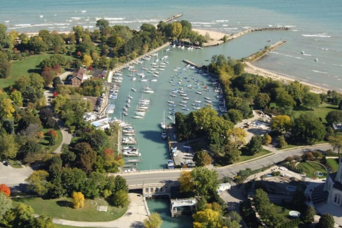 Optima Verdana luxury apartment with Aerial view of Wilmette marina with boats, surrounded by trees and shoreline, reflecting the area's rich history on a sunny day.