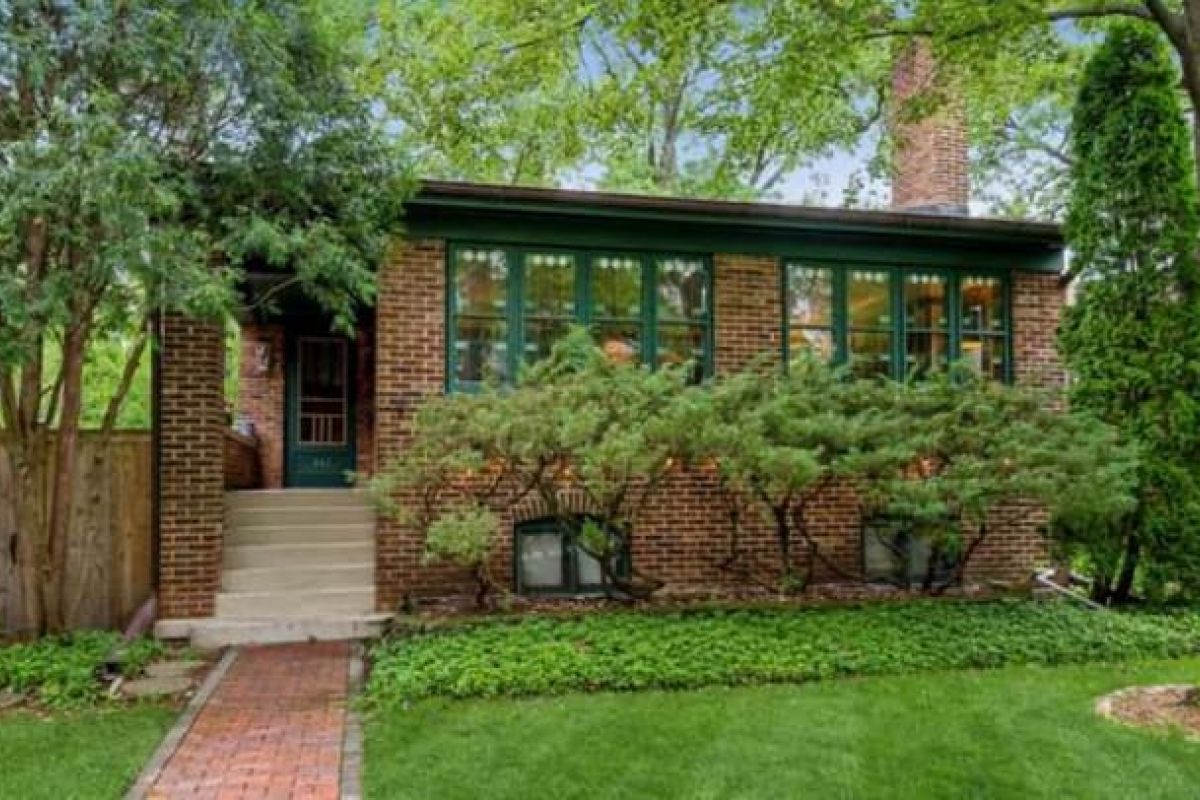 Optima Verdana luxury apartment with Single-story brick house with green trim, large windows, and lush yard in the charming Oak Circle Historic District.