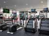 Optima Verdana luxury apartment with Modern gym for a healthy lifestyle with treadmills, weights, mirrors, TV screens, and towels in a bright, clean space.