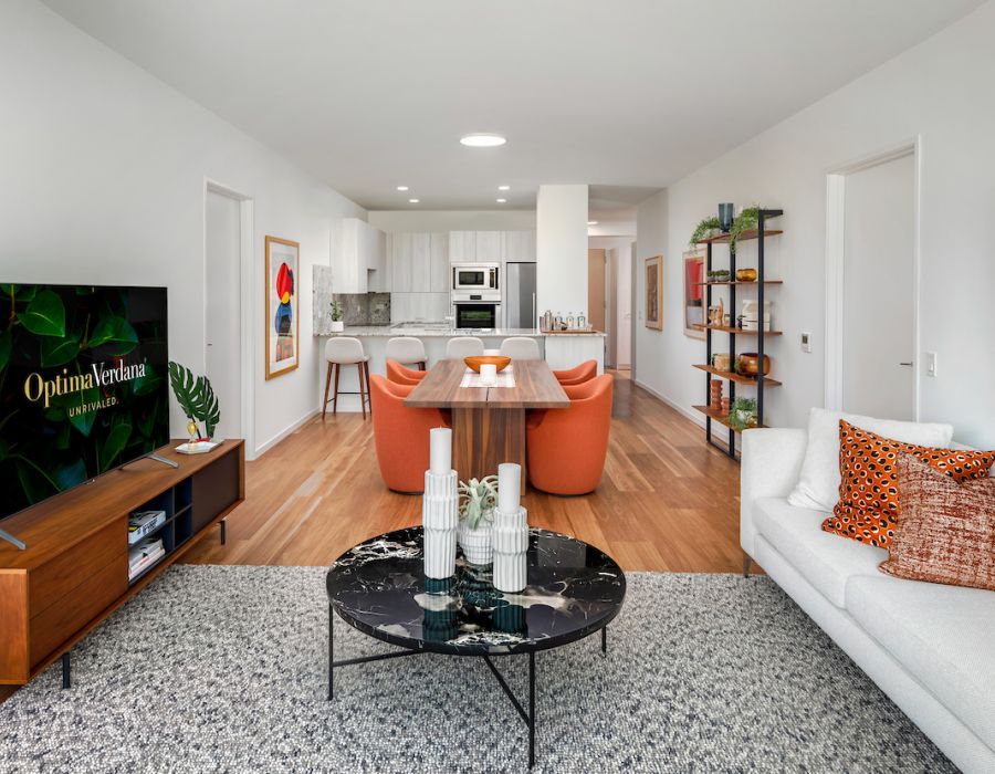 Optima Verdana luxury apartment with Modern open-plan living room and kitchen with stylish decor, orange chairs, and a TV on a wooden stand.