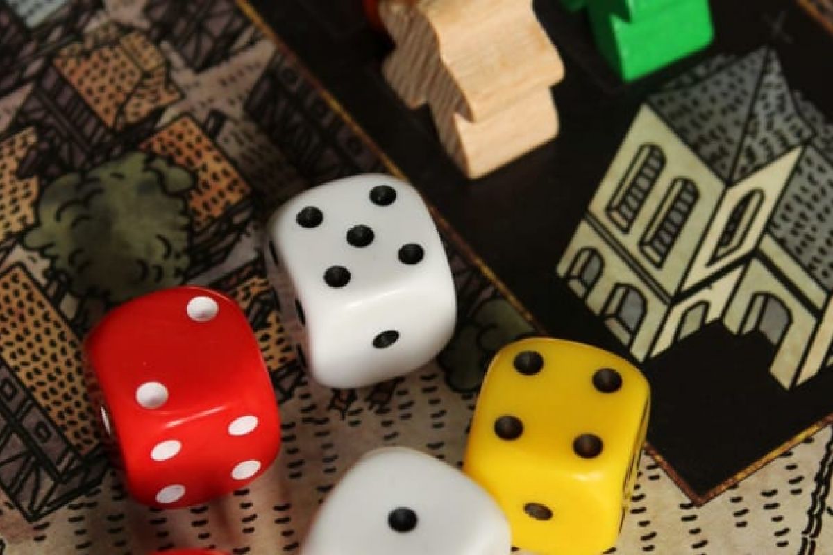 Optima Verdana luxury apartment with Four colorful dice and wooden pieces await Board Game Lovers on a vibrant board game with illustrated buildings and streets.