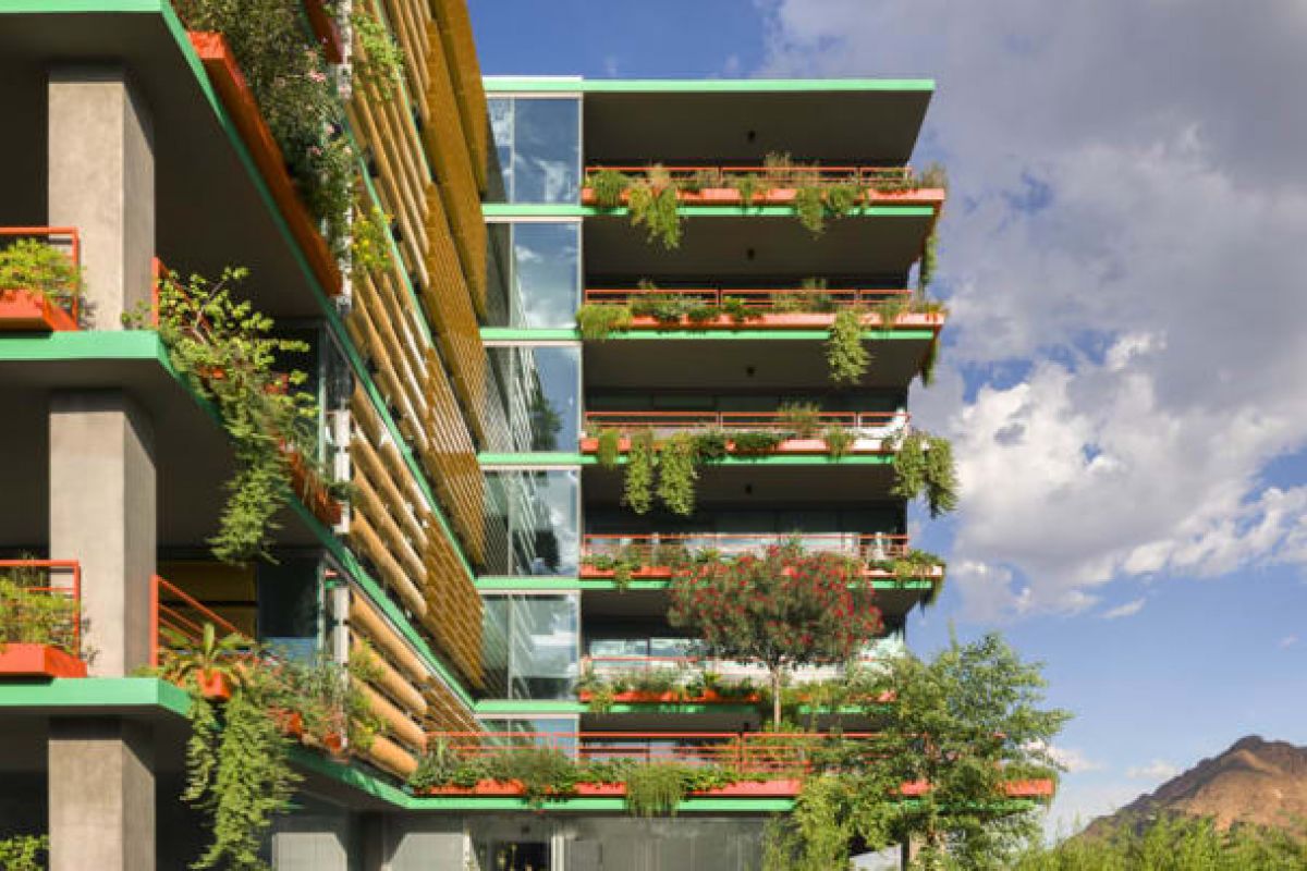 Optima Verdana luxury apartment with Modern building with colorful balconies, lush green walls, and vibrant plants, set against a blue sky and distant mountain.