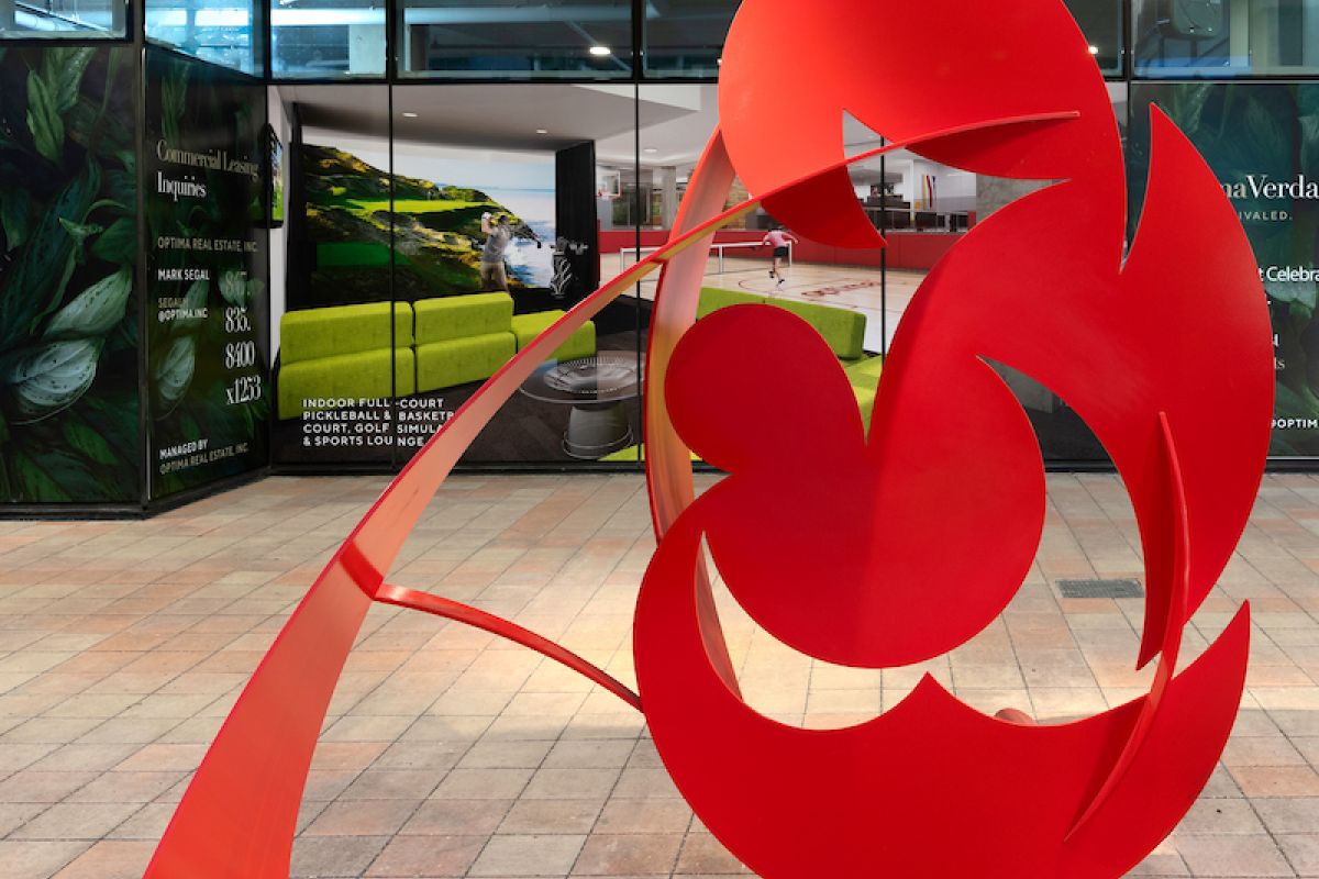 Optima Verdana luxury apartment with Bright red abstract metal sculpture with curved and circular shapes, displayed in an indoor public space.