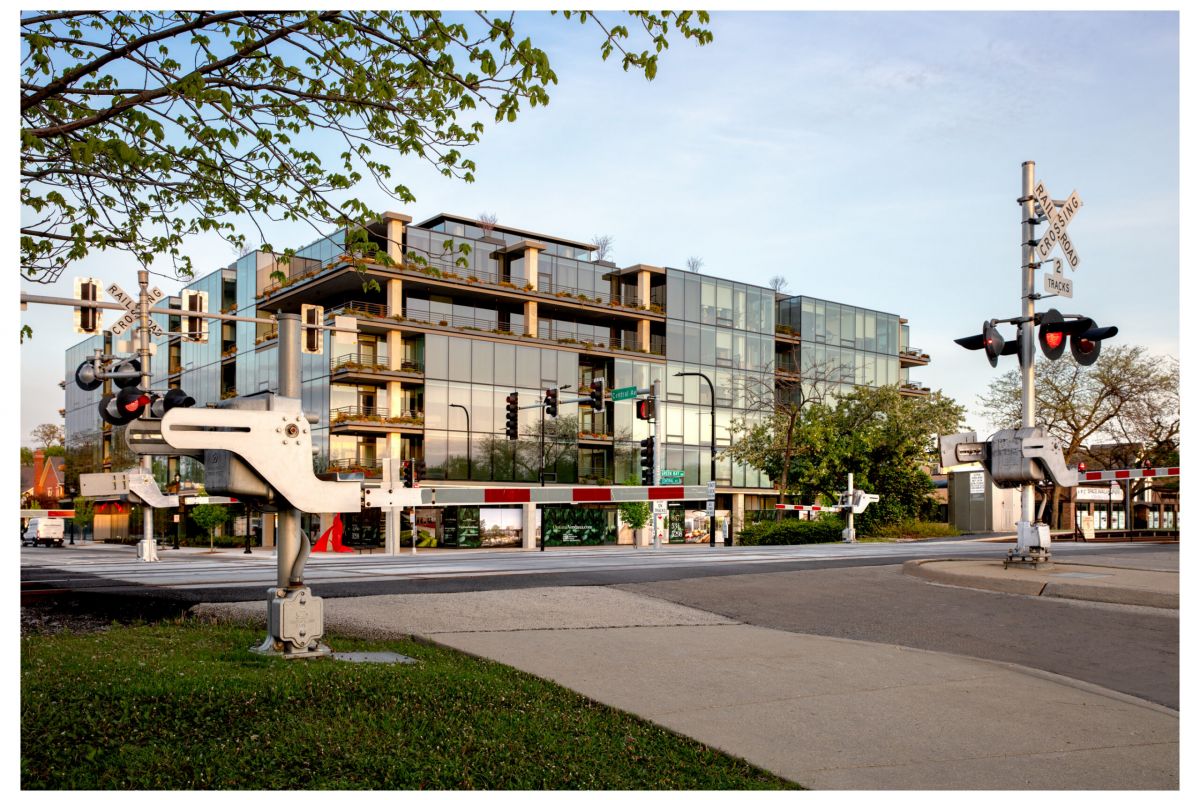 Optima Verdana luxury apartment with Modern glass building behind a railroad crossing, highlighting how sleep quality can be shaped by your home environment.