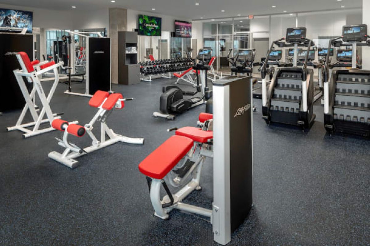 Optima Verdana luxury apartment with Modern gym with strength training machines, free weights, and cardio equipment on a dark speckled floor for maximum fitness.