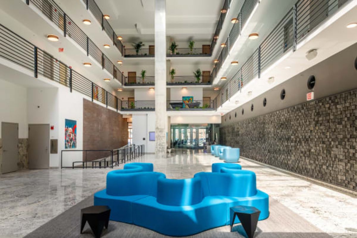 Optima Verdana luxury apartment with Modern, spacious building lobby with blue modular seating, natural stone walls, and striking architecture featuring upper floor balconies.
