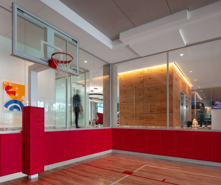 Optima Verdana luxury apartment with Modern indoor basketball court with red padding, glass walls, and a wood-paneled room in the background.