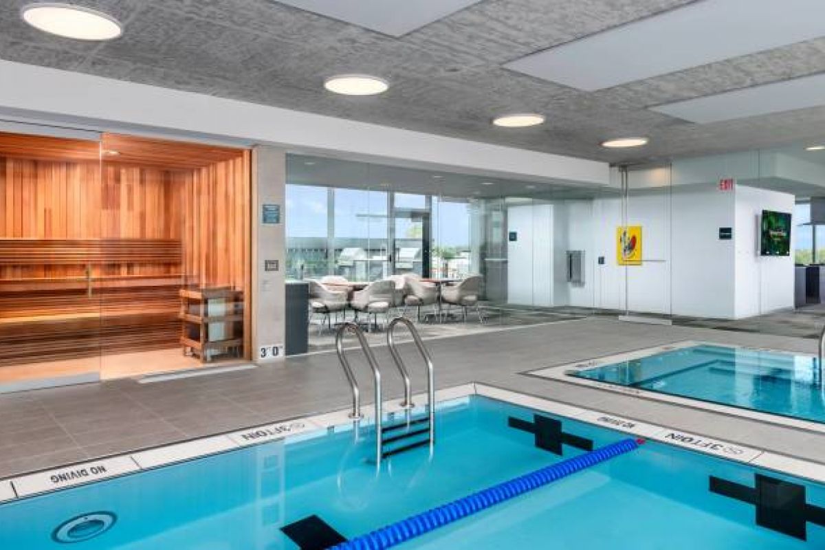Optima Verdana luxury apartment with Modern indoor pool area in luxury apartments features a hot tub, sauna, seating, large windows, and stunning city views.