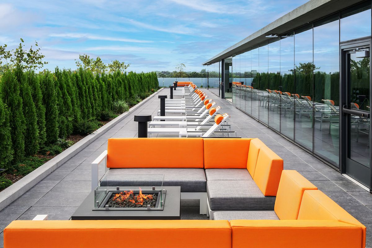 Optima Verdana luxury apartment with Modern rooftop patio for Optima Residents with orange seating, fire pit, and lounge chairs—choose to relax with sky views.