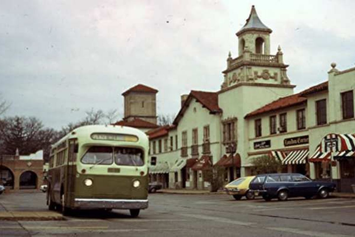 Optima Verdana luxury apartment with A vintage green and white bus drives past old shops and dining spots in the charming Plaza del Lago town square.