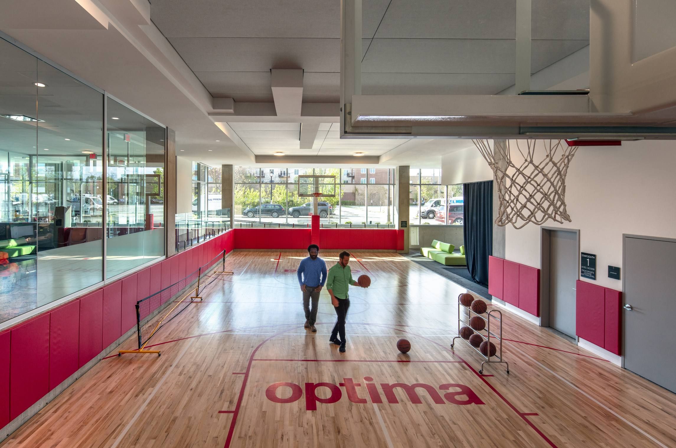 Optima Verdana luxury apartment with Two people walk on a modern indoor basketball court with "optima" on the floor and basketballs nearby.