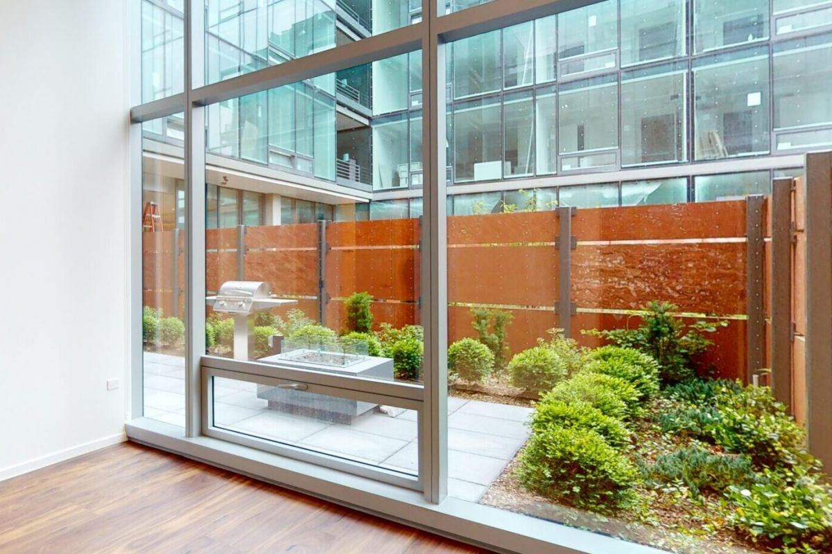 Optima Verdana luxury apartment with Modern room with wood floors, large windows, and views of a pet-friendly patio garden at Optima Verdana.