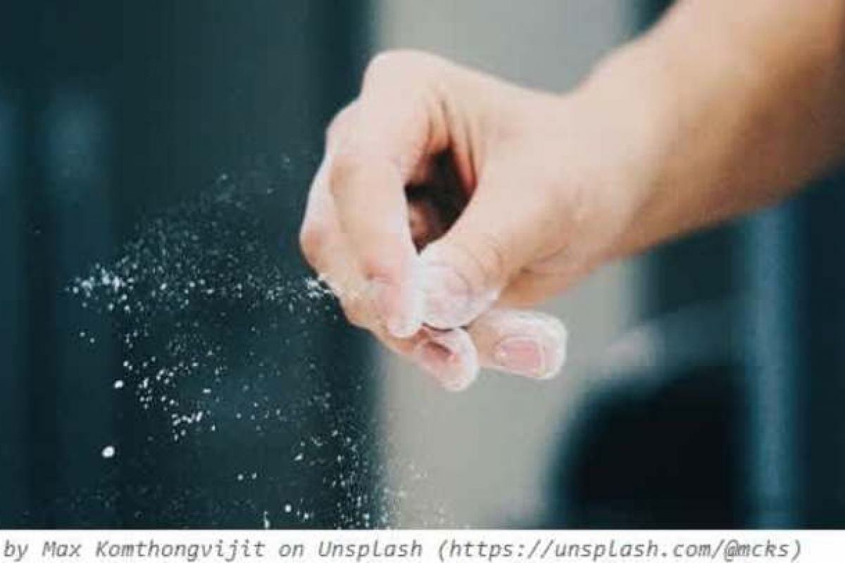 Optima Verdana luxury apartment with A hand sprinkles white powder, possibly flour or salt, against a blurred dark background—an Optima moment in sustainable living.
