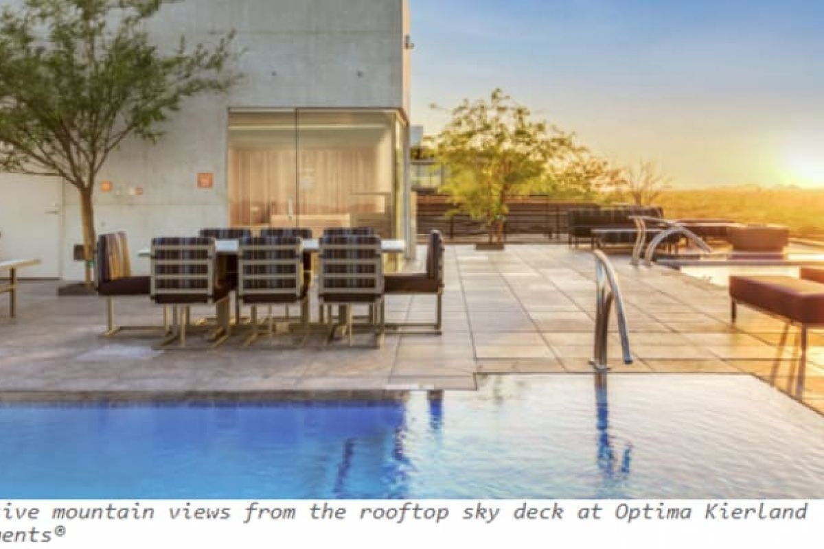 Optima Verdana luxury apartment with Rooftop pool and lounge area with mountain views at sunset, featuring modern seating and trees, shaping sustainability in urban design.