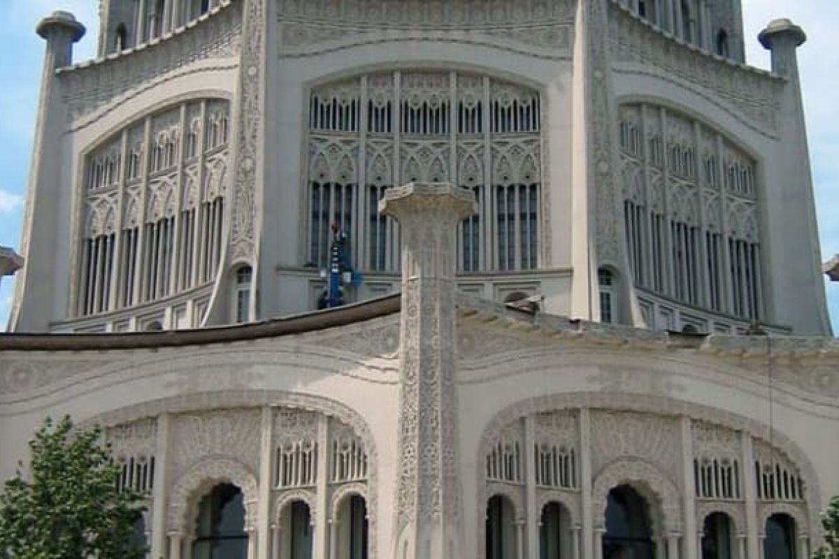 Optima Verdana luxury apartment with Ornate white Bahá'í Temple in Wilmette with intricate carvings, tall arched windows, and decorative columns against a blue sky.