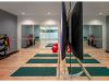 Optima Verdana luxury apartment with Exercise studio at Optima Verdana with yoga mats, Pilates balls, weights, mirrors, TV, wood floors, and modern lighting.