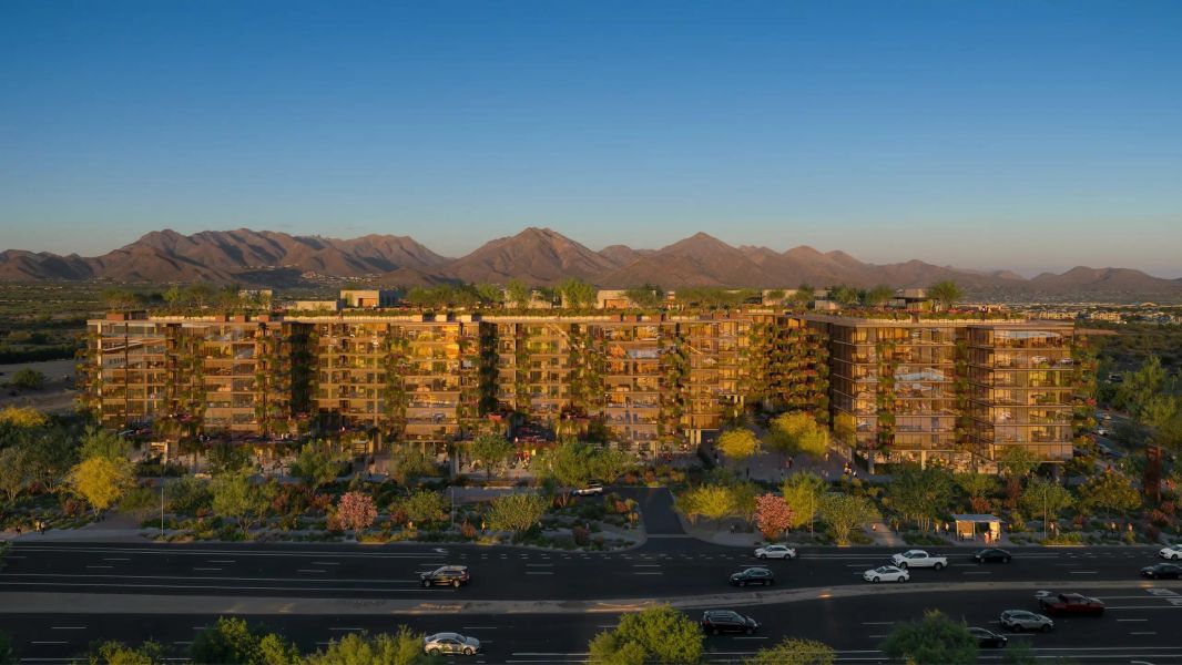 Optima Verdana luxury apartment with A modern, green-covered apartment complex with mountains in the background under a clear blue sky.