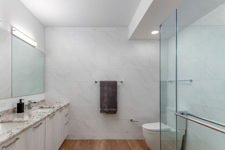 Optima Verdana luxury apartment with Modern bathroom with marble walls, a glass shower, dual sinks, and a towel hanging on the wall.