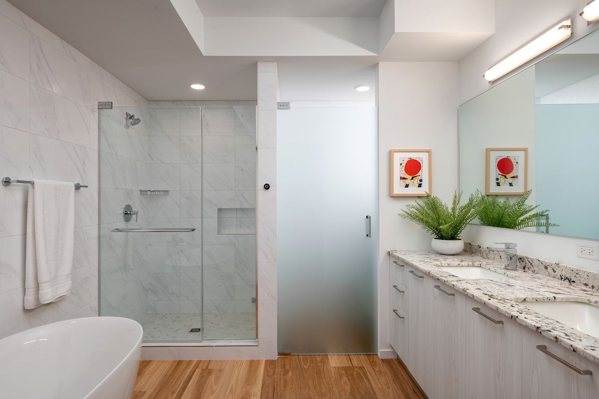 Optima Verdana luxury apartment with Modern bathroom design with glass shower, white countertop, potted plant, art, wood floor, and fresh towel—perfect for chic bathroom ideas.