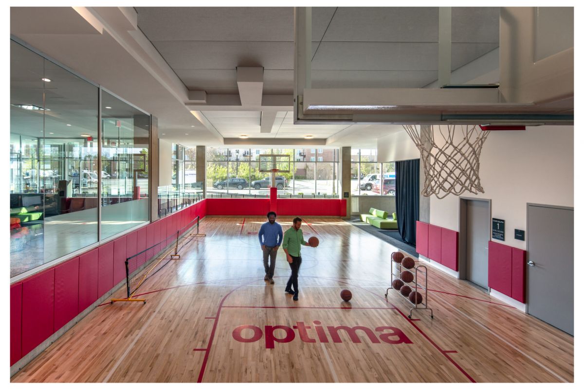 Optima Verdana luxury apartment with Two people walk on an indoor basketball court with "optima" written on the floor, enjoying daily life in the Optima Community.