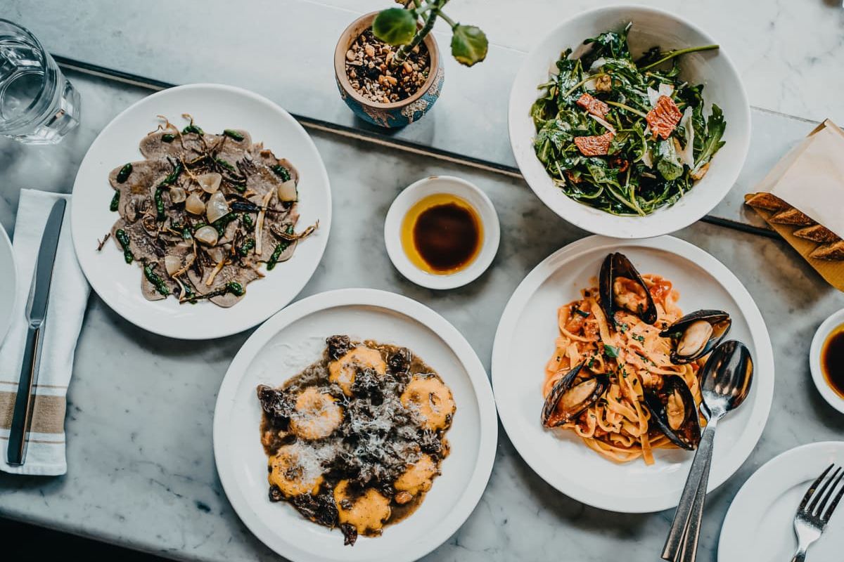 Optima Verdana luxury apartment with Four plates of Italian food, including pasta and salad, arranged on a marble table at Wilmette’s favorite spot near Chicago.