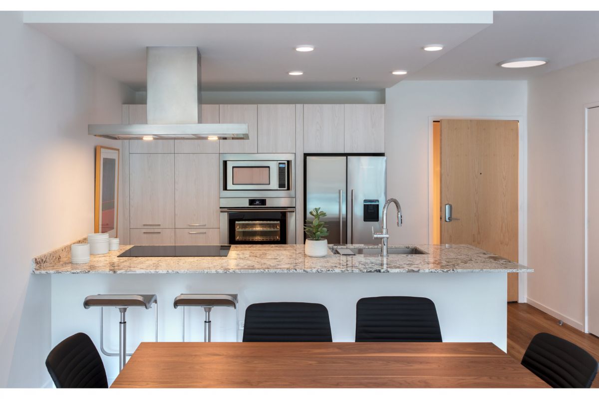 Optima Verdana luxury apartment with Modern kitchen in Optima Verdana one-bedroom residences, featuring light wood cabinets, stainless steel appliances, and a marble island.