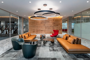 Optima Verdana luxury apartment with Modern office lounge with brown leather sofas, a red accent chair, and circular ceiling lights.