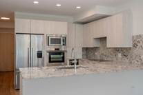 Optima Verdana luxury apartment with Modern kitchen with white cabinets, stainless steel appliances, and marble countertops and backsplash.