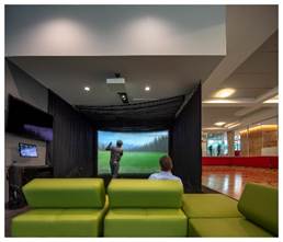 Optima Verdana luxury apartment with A person plays golf in an indoor simulator while another sits on a green couch watching in a modern room.