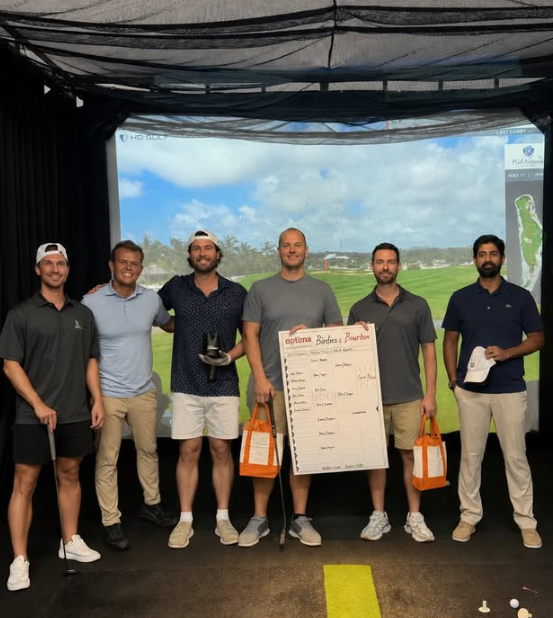Optima Verdana luxury apartment with Six men standing in an indoor golf simulator, with one holding a scoreboard labeled “Birdies & Bourbon.”